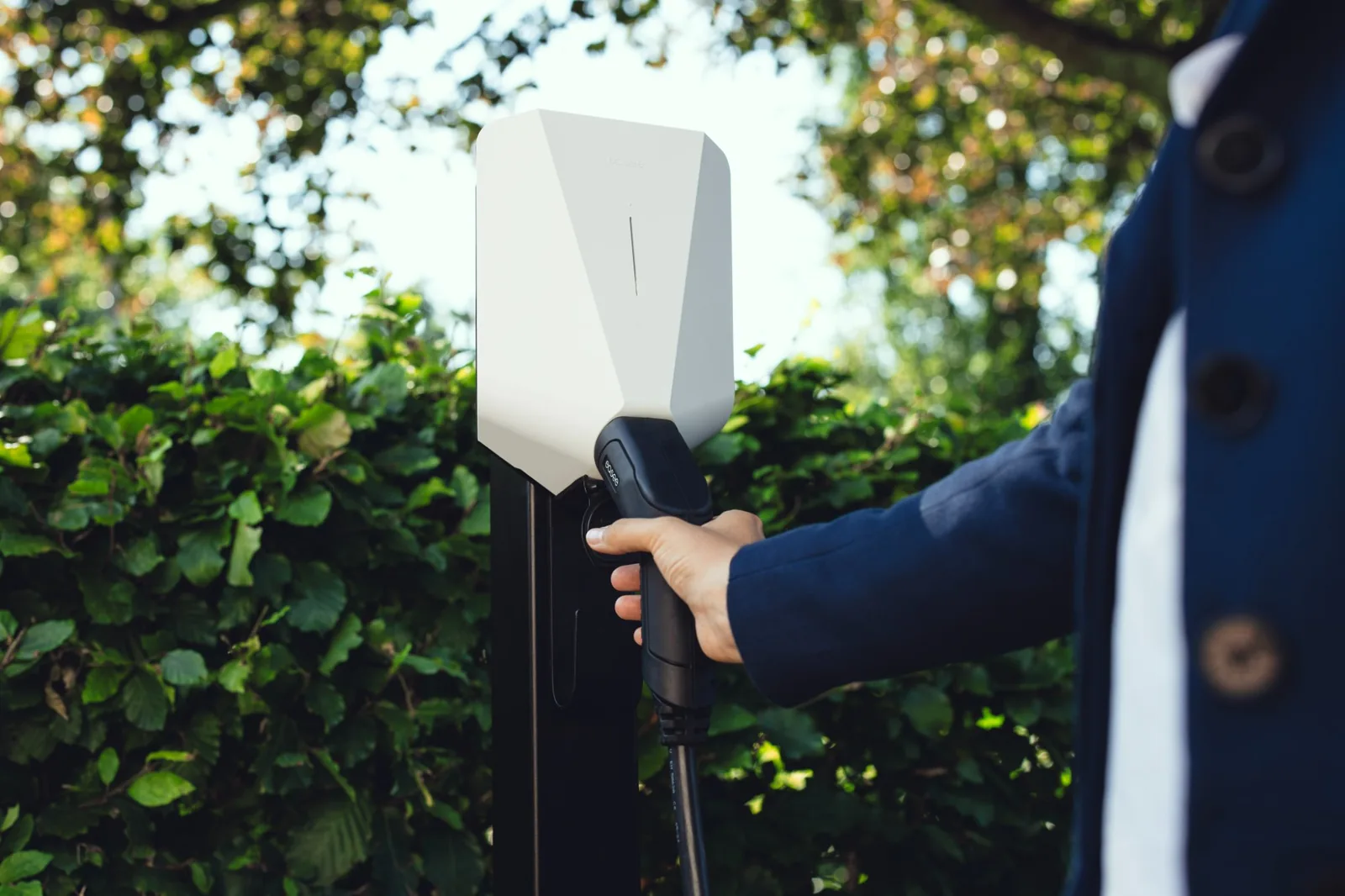 Easee Charge Up monterad på stolpe, med laddkabeln i handen