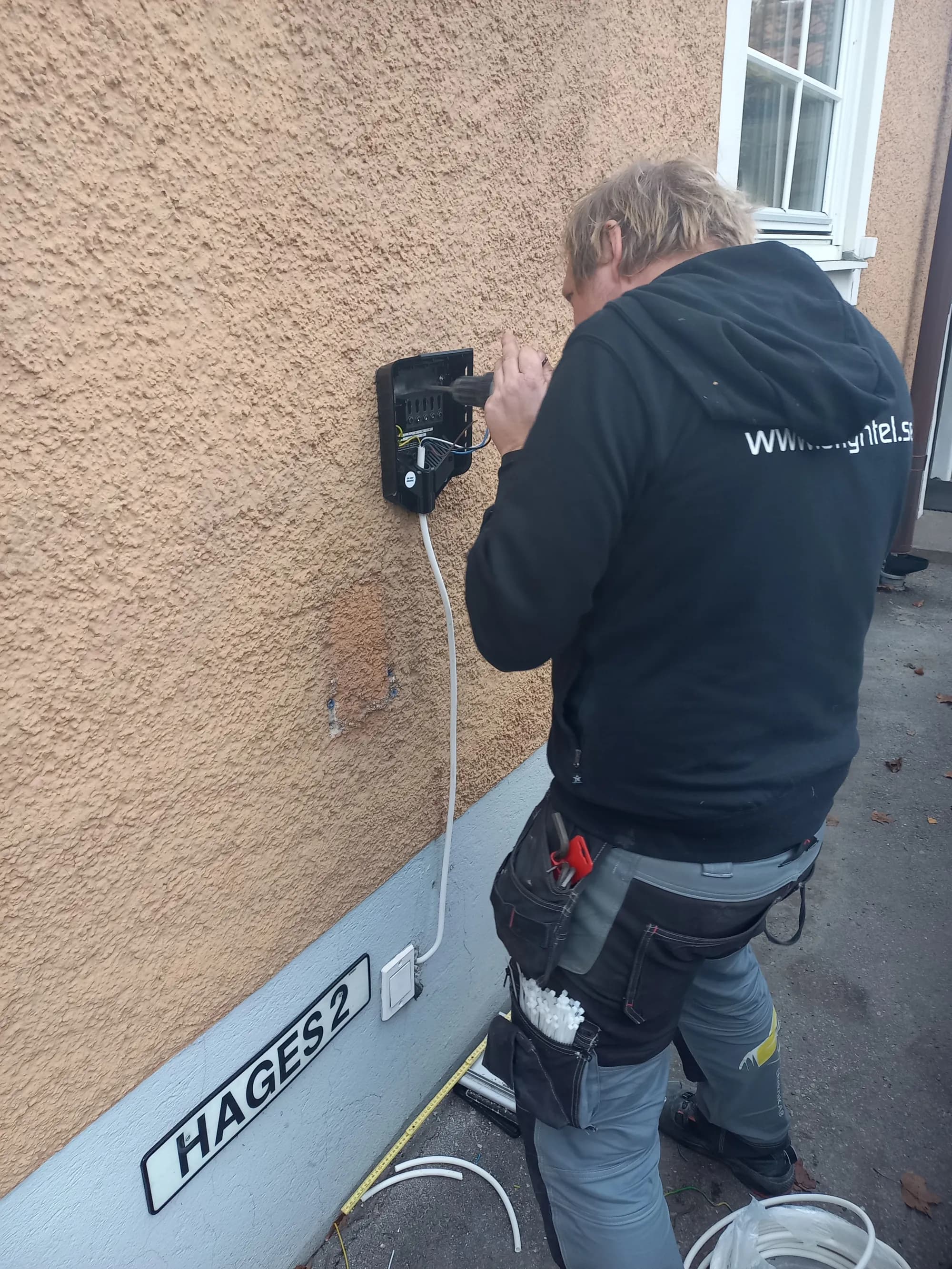 Elektriker installerar laddbox på husfasad