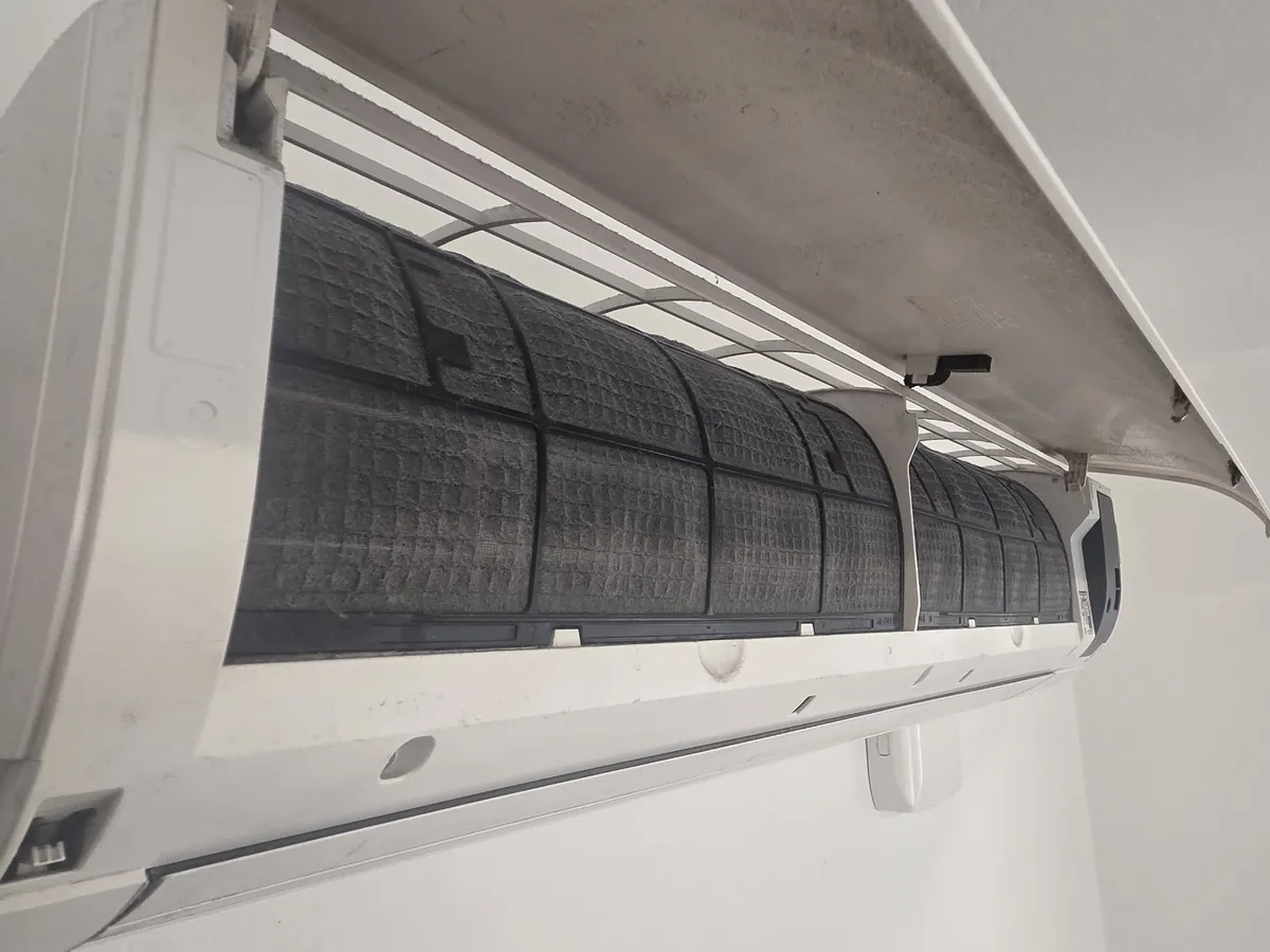 Innedel på en Daikin luftvärmepump med fronten uppfälld – filtren är täckta av damm inför service